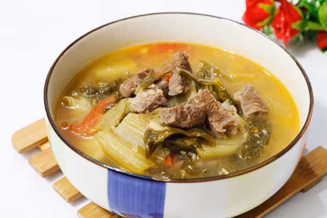 Bước 5: Trút tất cả hỗn hợp dưa xào vào nồi canh, nấu cho sôi thì nêm chút xíu đường để nồi canh có hương vị hài hòa, nấu thêm 5 phút là tắt bếp. Múc canh dưa chua nấu thịt dải sườn bò ra tô dùng nóng.