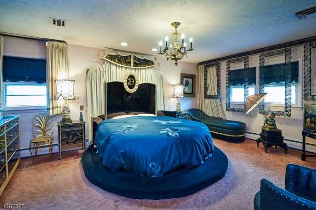 Mỗi phòng ngủ đều có một tông màu hoàn toàn riêng biệt, ví dụ như phòng này là màu xanh đậm. Chiếc giường tròn có niên đại hàng chục tuổi nhưng tới giờ vẫn vô cùng thời thượng.