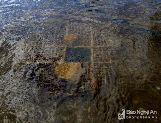 Chiếc bẫy cá được đè bởi hai hòn đá để giữ thúng cân bằng không bị trôi, sau đó rắc một ít lạc rang đã giã nhỏ bỏ vào trong bẫy. Ảnh: Bé Vinh