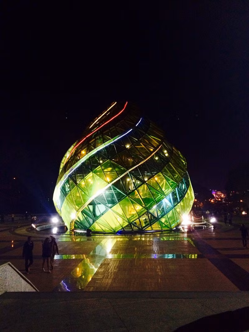 Tọa lạc giữa “trái tim” của Đà Lạt, nụ hoa atiso cao 15 m cùng đóa dã quỳ cao 18 m là điểm thu hút nhiều du khách. Nhờ thiết kế bằng kính màu chịu lực, trong ánh đèn đêm của quảng trường Lâm Viên, công trình hiện lên huyền ảo, khiến du khách như đang lạc vào xứ thần tiên. Ảnh: Pan.