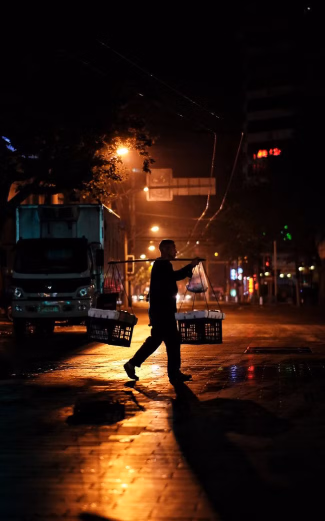 Người đàn ông gánh hàng bán rong trên đường phố đêm ở Thượng Hải.