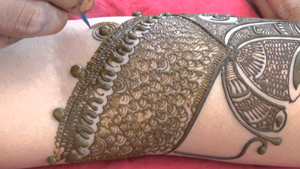 Theo truyền thống, bột Mehndi được làm từ lá henna khô. Lá được phơi khô trong nắng, giã nát và lọc để lấy bột màu xanh lá cây. Sau đó hòa tan trong nước, nước chanh, tinh dầu bạch đàn, và một vài nguyên liệu khác. “Mực Mehndi” được ngâm qua đêm sau đó đổ vào trong một phễu nhựa, cắt ở đầu, tương tự phễu vắt kem. Miếng cắt to nhỏ sẽ tùy heo độ đậm nhạt của nét vẽ. Ảnh: MehndiArtistica/Youtube.