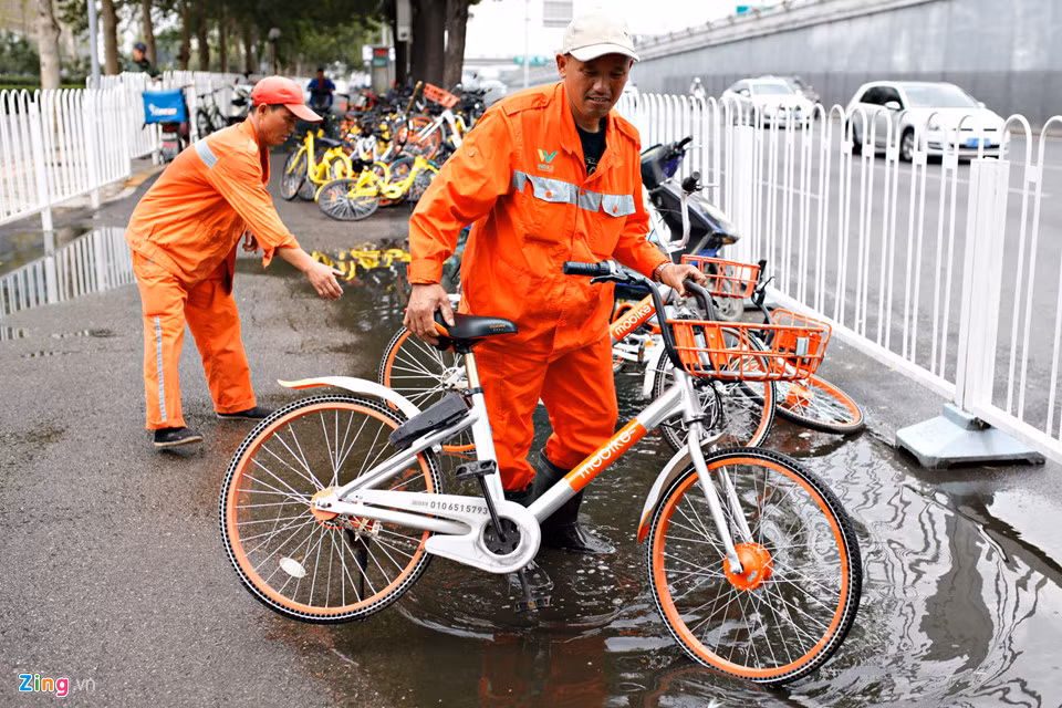 Một nhóm công nhân đang sắp xếp lại những chiếc xe ngổn ngang sau cơn mưa. Họ phải làm việc liên tục vì những bãi đậu xe như thế này có ở mọi ngóc ngách thành phố.