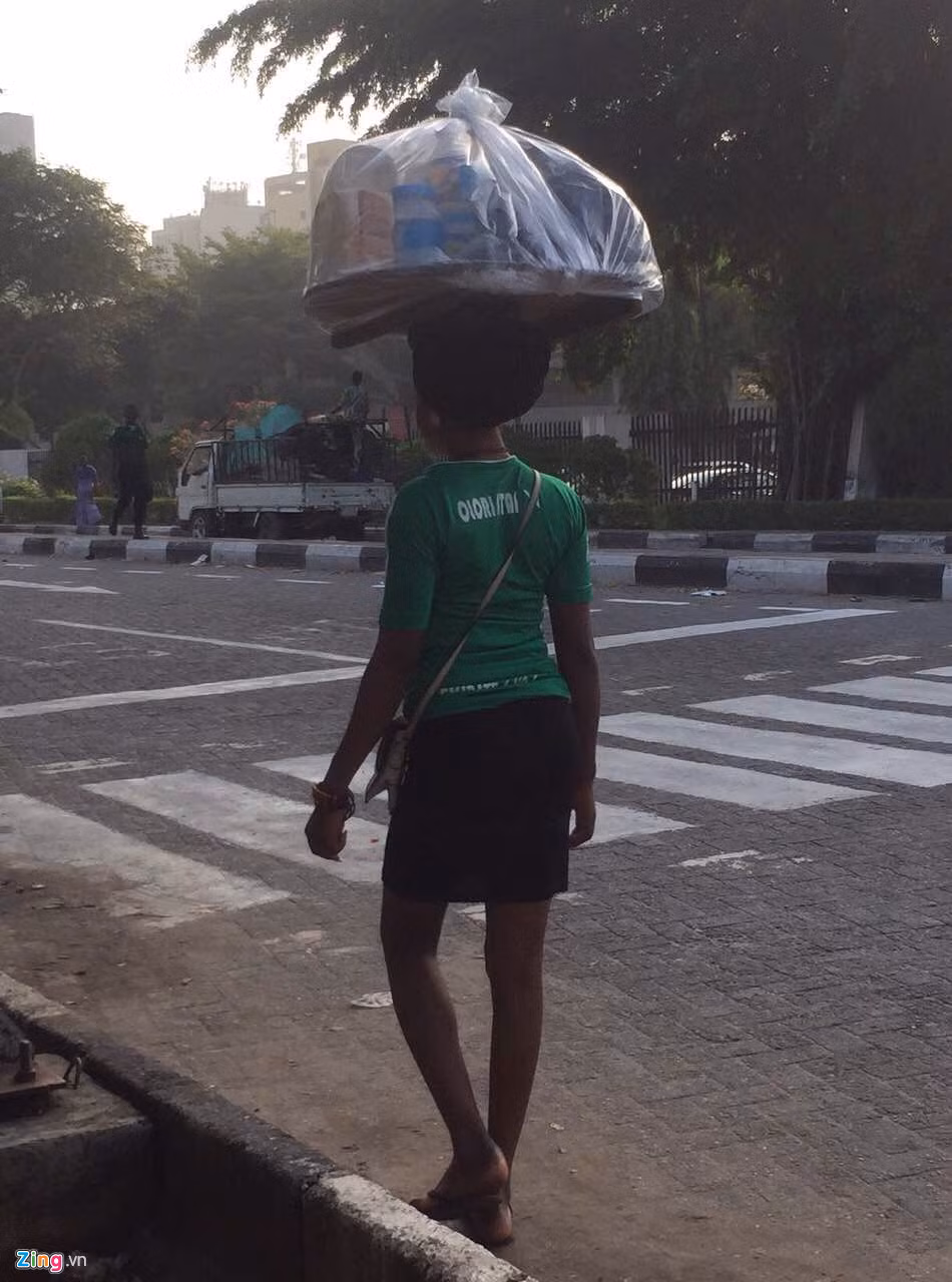 Một người bán hàng rong ở thành phố Lagos, Nigeria. Lagos là thành phố lớn nhất Nigeria và là một trong những thành phố đông dân nhất châu Phi. Thành phố là trung tâm tài chính của Nigeria và từng là thủ đô của quốc gia này. Đây là nơi có mức sống cao, có nhiều người giàu nhưng chênh lệch giàu nghèo cũng rất lớn.