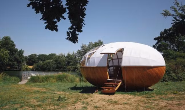 Nhìn một cách hình dung hóa, ngôi nhà gỗ này bắt mắt người xem ngay cái nhìn đầu tiên ở diện mạo kiến trúc. Nó trông giống như một quả trứng ngỗng khổng lồ sơn hai màu nâu-trắng bổ đôi một cách quái lạ.