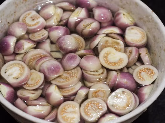 Cách làm: Bước 1 Cà cắt bỏ cuống, cắt đến đâu bạn thả ngay cà đến đó vào nước muối để cà không bị thâm. Cắt cà thành từng miếng mỏng, ngâm vào nước muối với dấm trắng khoảng 30 -45 phút để miếng cà trắng, không bị thâm đen.