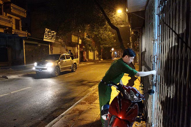 Công an phường Vĩnh Hưng (quận Hoàng Mai) nhắc nhở người dân đóng cửa trong khi xe phun thuốc diệt muỗi làm việc.