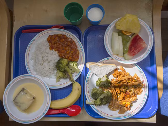 London, Anh: Suất ăn bên phải có mì ống, súp lơ xanh, bánh mỳ và trái cây theo mùa. Một lựa chọn khác là: súp rau, cơm, súp lơ xanh, bánh bông lan trứng sữa và một quả chuối.