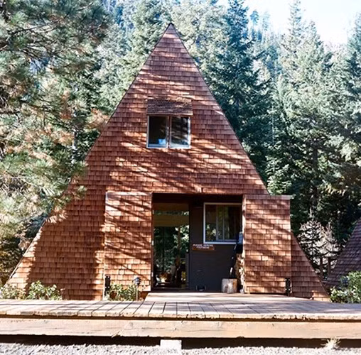 Ngôi nhà hình tam giác độc đáo này được ốp gạch màu nâu sáng giúp nó như hòa mình vào cảnh quan thiên nhiên giữa rừng.