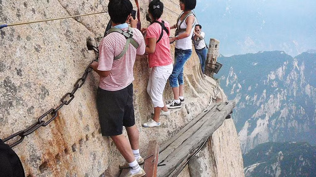 Huashan là một trong 5 ngọn núi thiêng của Đạo giáo ở Trung Quốc với đỉnh cao nhất hơn 2.133 m. Du khách thích phiêu lưu có thể trải nghiệm đi trên con đường bằng gỗ gắn vào sườn núi rất đáng sợ. Ảnh: Youtube.