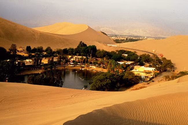 2. Huacachina, Peru Huacachina là một xứ sở thần tiên nằm giữa các cồn cát khô nóng ở Peru. Ốc đảo có một ngôi làng nhỏ và hồ mát trong và nhiều cây xanh. Địa điểm này cũng thu hút rất đông du khách tới tham quan.