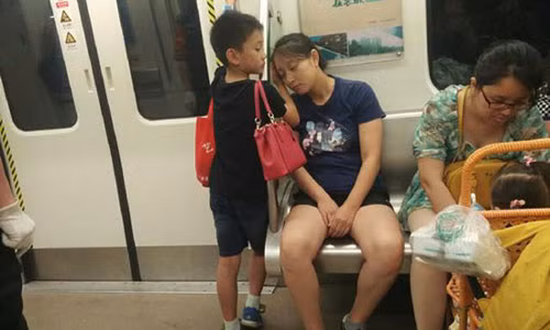 Cam dong be trai dung tay lam goi cho me ngu tren tau dien