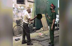 Ông cụ còn cầm chiếc mũ cối, giơ ra phía trước và bắt đầu nặng lời, đe dọa đồng chí công an, quát lớn.