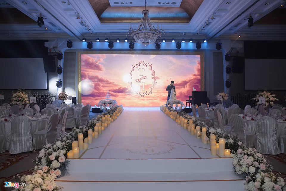 Đường dẫn lên sân khấu khá lãng mạn với hoa tươi và nến được trang trí ở hai bên. Trên sân khấu có sẵn đàn piano để phục vụ cho các tiết mục văn nghệ trong tiệc cưới. Trước giờ diễn ra, nhân viên khách sạn kiểm ra lại các chi tiết lần cuối.