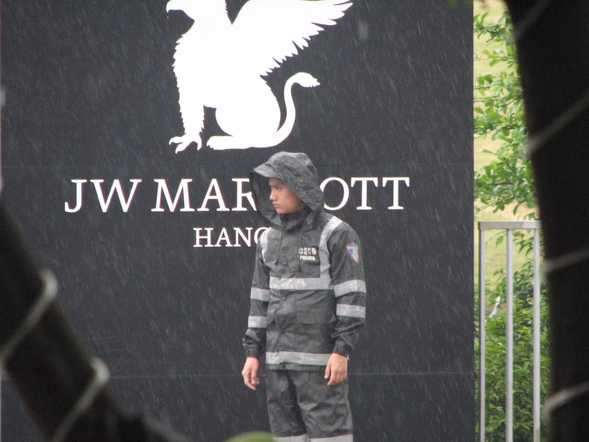 Một cảnh sát cơ động làm nhiệm vụ an ninh trước cổng khách sạn Marriott đang mặc áo mưa.