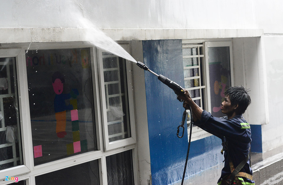 Công nhân đu dây để rửa sạch bên ngoài những khu vực mảng tường bị ám khói đen.