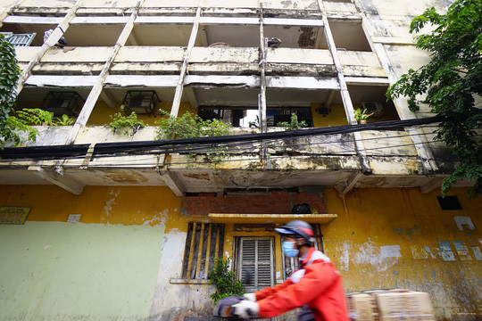 Phần hành lang nối lô A và lô B chung cư Vĩnh Hội đã bị lún sụp và người dân phải che chắn tạm để tránh nguy hiểm. Một phần tường trên trần nhà bị nứt rất dài kéo xuống tới nền gạch. Ảnh: NLĐ.