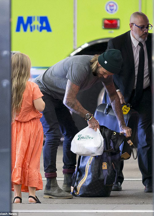 Ông bố bốn con kiểm tra túi đồ của mình trong khi một phụ tá xách chiếc túi của Victoria.