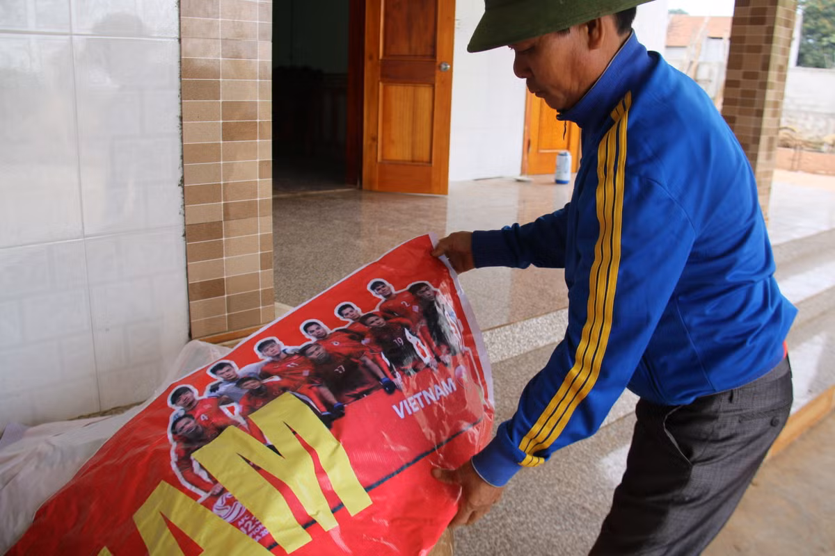 Ông Phạm Xuân Linh (SN 1964), bố của cầu thủ Duy Mạnh, chuẩn bị tấm băng rôn để đón con và đồng đội tại TP Vinh. Ảnh: Ngọc Trang.