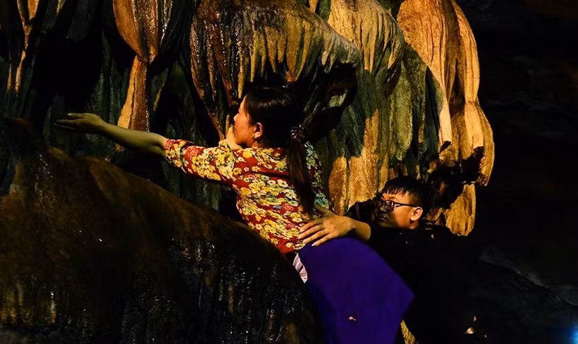 Bất chấp vách đá nguy hiểm, trơn trượt đôi nam nữ vẫn giúp nhau hứng "nước lộc".