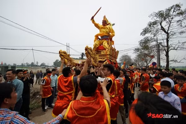 Trong khi rước, thỉnh thoảng đám trai tráng khênh kiệu “chúa” lại hô vang rồi chạy để dẹp đường cho “vua”. Ảnh: Tường Bách.