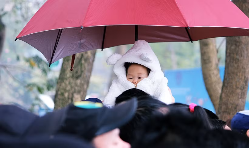 Thậm chí có cả những em bé rất nhỏ tuổi cũng được người thân mặc kín áo ấm, che ô tránh mưa đưa đến hồ Tây xem đua thuyền rồng.