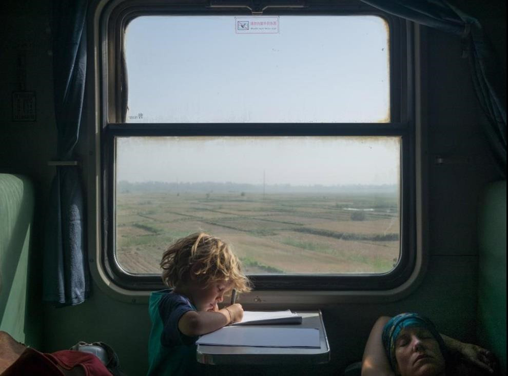 Tân Cương (Trung Quốc): Nhiếp ảnh gia Matthieu Paley nhanh chóng bắt được khoảnh khắc thú vị trong những giờ cuối cùng trên chuyến xe lửa rong ruổi khắp Trung Quốc. Cậu bé Timo (5 tuổi) trong ảnh tỏ ra rất thích thú khi vẽ lại gương mặt mẹ lúc ngủ.