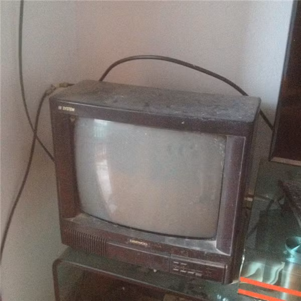 Chiếc ti vi bám đầy bụi, nhỏ nhỏ, có màn hình lồi, khác hẳn với những thiết kế siêu mỏng hiện đại bây giờ.