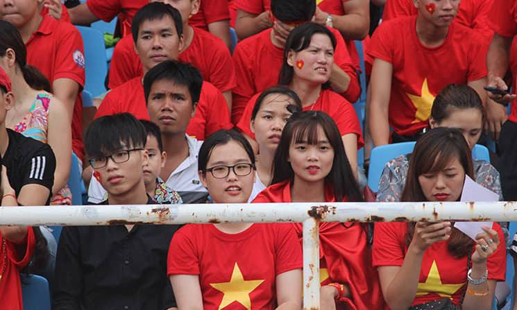 Trên khán đài là "biển" cổ động viên mặc áo đỏ sao vàng, reo hò cổ vũ sôi động.