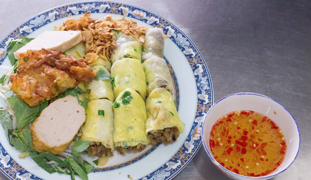 Bánh cuốn trứng: Bạn có thể ăn bánh cuốn trứng tại Hà Nội nhưng muốn ăn cho chuẩn vị thì nhất định nên đến Lạng Sơn. Bánh sau khi tráng được đập thêm một quả trứng rồi đậy vung cho trứng chín hơi. Bên trên đĩa bánh rắc thêm thịt băm và hành khô. Điểm đặc biệt là nước chấm ở đây không phải nước mắm pha bình thường mà có một chút thịt xay khô, thêm rau mùi với nước chấm mỡ hành. Thêm vào đó, mỗi bàn ăn đều có một lọ măng ngâm ớt để khách hàng tùy ý chỉnh vị cho bát nước chấm của mình. Ảnh: Vtimes, Dacsanthonque.