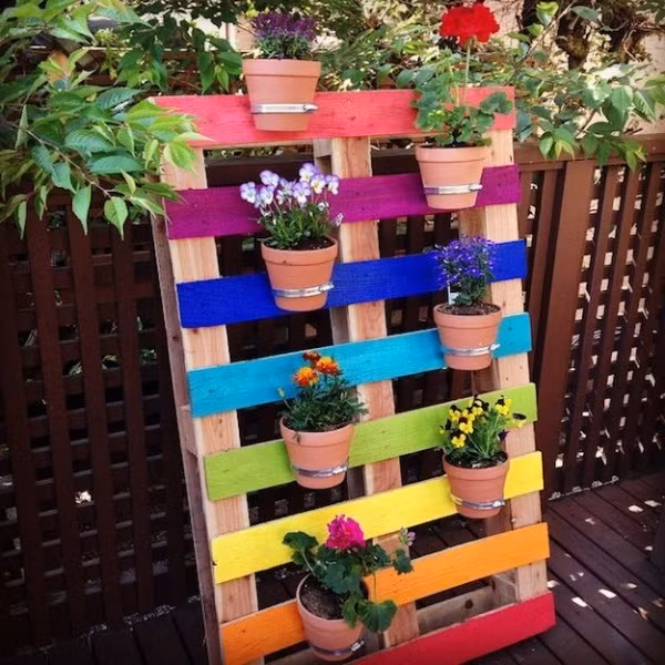 Tấm pallet vô cùng ấn tượng được sử dụng để gắn các chậu cây lên trên. Góc nhỏ ấn tượng hơn nhờ ý tưởng sơn các tấm pallet với nhiều màu khác nhau.
