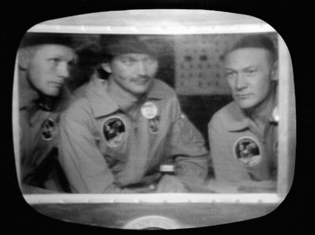 Bên trong buồng cách ly Mobile Quanrantine Facility (MQF) là Neil Amstrong, Michaeal Collins và Edwin Buzz Aldrin của tàu Apollo 11 đã đáp xuống Thái Bình Dương, cách phía Tây đảo Hawaii 812 hải lý, chỉ cách tàu sân bay U.S.S Hornet 12 hải lý.