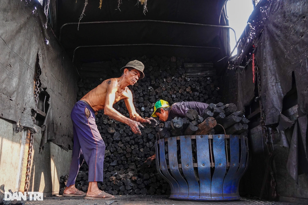 Cánh đàn ông chất than lên xe tải, mang hàng đi giao.