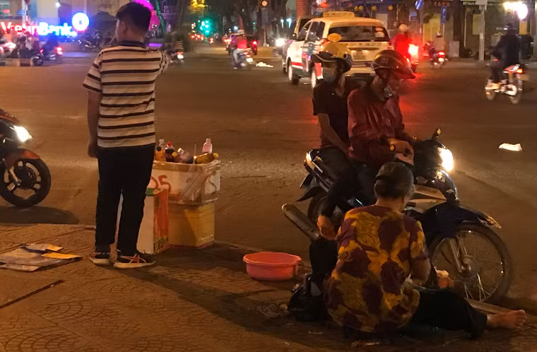 Hơn 30 năm nay, bà Trần Thị Ngọc Anh (60 tuổi, ngụ quận 4, TP HCM) cặm cụi làm công việc vá xe đêm bên vỉa hè góc đường Nam Kỳ Khởi Nghĩa - Hàm Nghi, quận 1 để nuôi đứa cháu ngoại. Đêm giao thừa Tết Mậu Tuất, đứa cháu ngoại cũng "xuống đường" để phụ với bà bán nước, sửa xe cho khách đi ngắm pháo hoa.