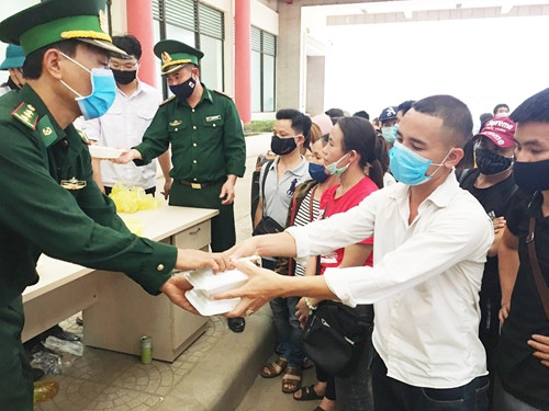 Bộ đội biên phòng phát khẩu phần ăn cho người Việt về nước qua lối đường bộ đang chờ đi cách ly. Nguồn ảnh: QĐND.