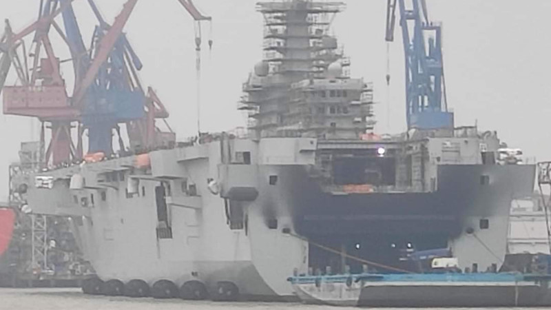 Tình trạng của tàu đổ bộ Type 075 sau vụ cháy hôm 11/4 vừa rồi, có thể thấy vụ cháy xuất phát từ phía bên trong tàu, khiến khói đen bao trùm một phần thân tàu. Nguồn ảnh: QQ.