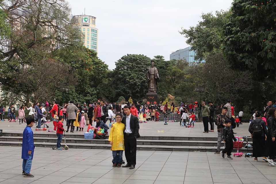 Nhiều em nhỏ trong trang phục áo dài truyền thống đi du xuân, ngắm cảnh cùng gia đình và chụp ảnh tại tượng đài Lenin.