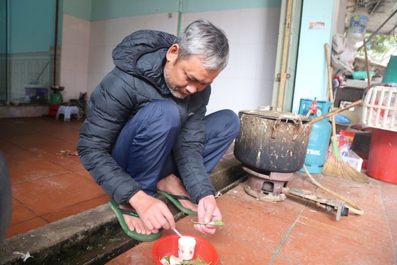 Một người đàn ông thong thả ngồi têm trầu trước hiên nhà.