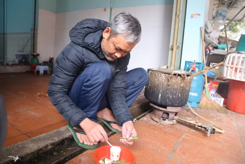 Một người đàn ông thong thả ngồi têm trầu trước hiên nhà.