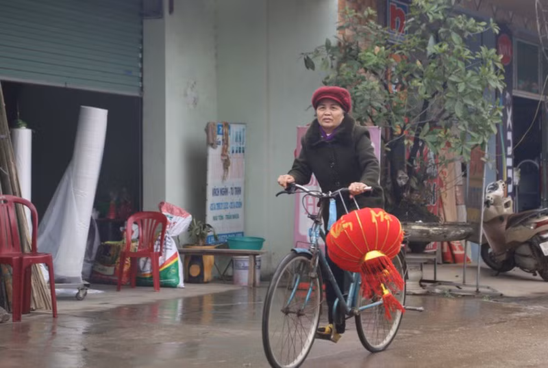 Một phụ nữ mua đèn lồng về trang trí nhà cửa đón Tết. Cũng như khắp mọi miền đất nước, Xuân đang về với thôn Hoành.