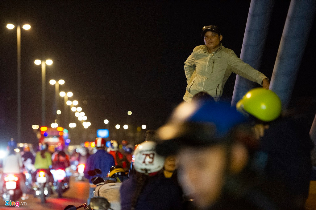 Một thanh niên trèo lên thành cầu để tiện quan sát dòng người từ hướng Tiền Giang đổ về Vĩnh Long. Việc đi xe máy và dừng lại tham quan cầu Mỹ Thuận trong đêm là một trong những trải nghiệm thú vị trong hành trình về quê ăn Tết.