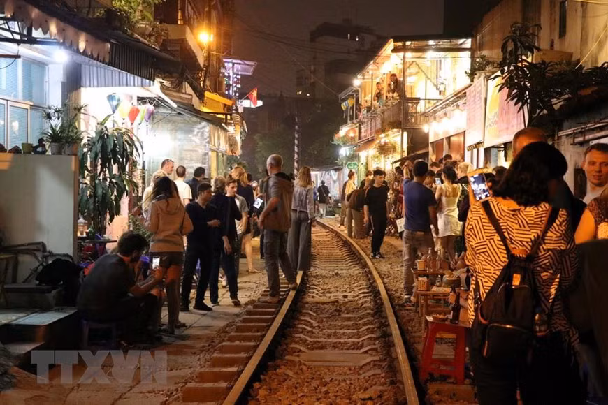 Du khách nước ngoài đến "xóm đường tàu" Hà Nội ngày một đông, đặc biệt là vào những ngày cuối tuần khi có nhiều chuyến tàu chạy qua trong ngày. (Ảnh: Vi Thương - Hải Yến/TTXVN).