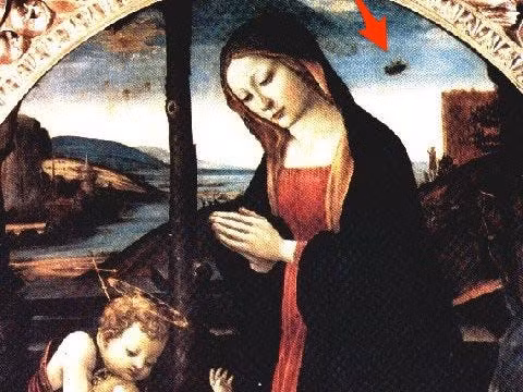 Vật thể mờ hình tròn trong bức tranh nổi tiếng "Madonna with Saint Giovannino" của Domenico Ghirlandaio từng là tâm điểm tranh cãi trong nhiều năm. Một số người thậm chí cho rằng đó là hình ảnh của một phi thuyền của người ngoài hành tinh. Mặc dù nhìn ở đây trông có vẻ không giống lắm nhưng khi phóng to lên, vật thể này thực sự có hình dạng của một UFO.