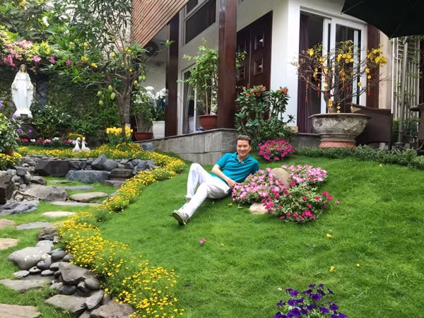 Lối đi trong vườn được rải sỏi dẫn vào tận nhà. Hai bên lối đi cỏ xanh mướt, các loài hoa thi nhau đua nở tạo nên khung cảnh đẹp thơ mộng. Ảnh: VTC News.