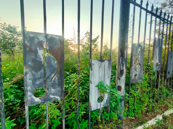 Hàng rào sắt bao quanh công viên bị hoen gỉ, phai màu và xuống cấp theo thời gian. 