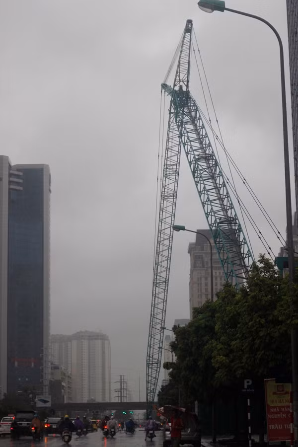 Một chiếc cần cẩu của công trường xây dựng gãy cắm xuống đường trong mưa bão trên phố Dương Đình Nghệ.