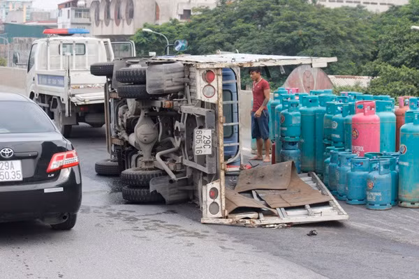 Chiếc xe tải lật khiến toàn bộ số bình gas trên thùng xe bay tung tóe ra đường.