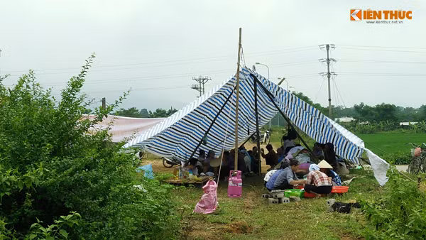 Hàng trăm người dân xã Tân Tiến chia đều nhau ra ngồi ở hai chiếc lán dựng bằng bạt.