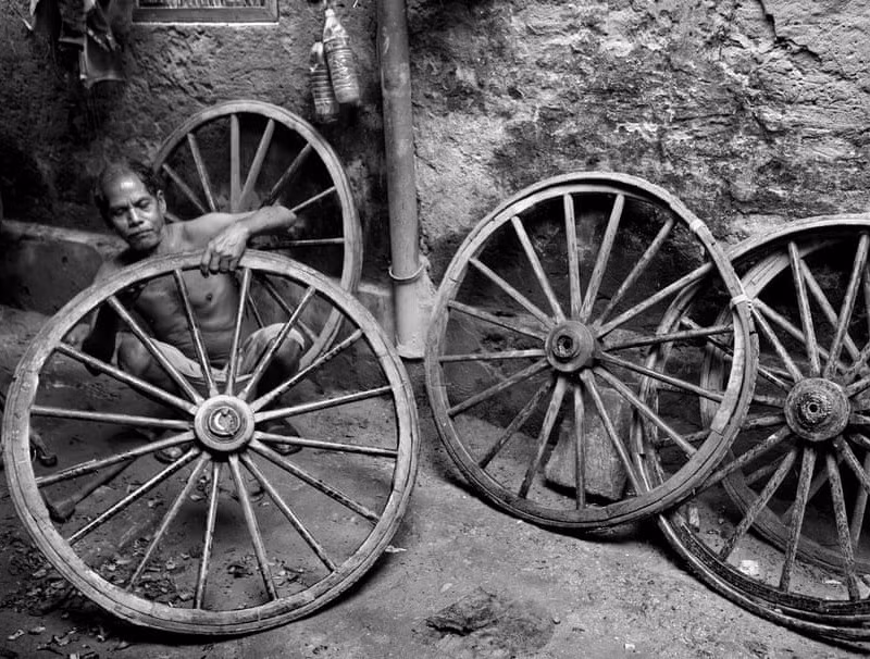 Người đàn ông tranh thủ sửa chữa bánh xe bị hỏng để tiếp tục hành nghề. 