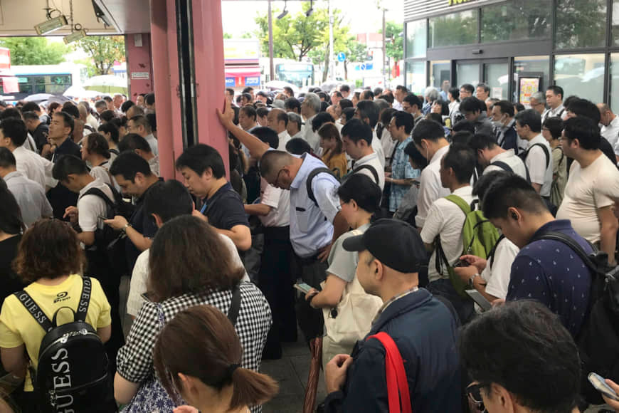 Nhiều hành khách đứng chờ bên ngoài một nhà ga ở Yokohama sau khi dịch vụ đường sắt tạm ngừng hoạt động vì bão Faxai hôm 9/9. Ảnh: AP.